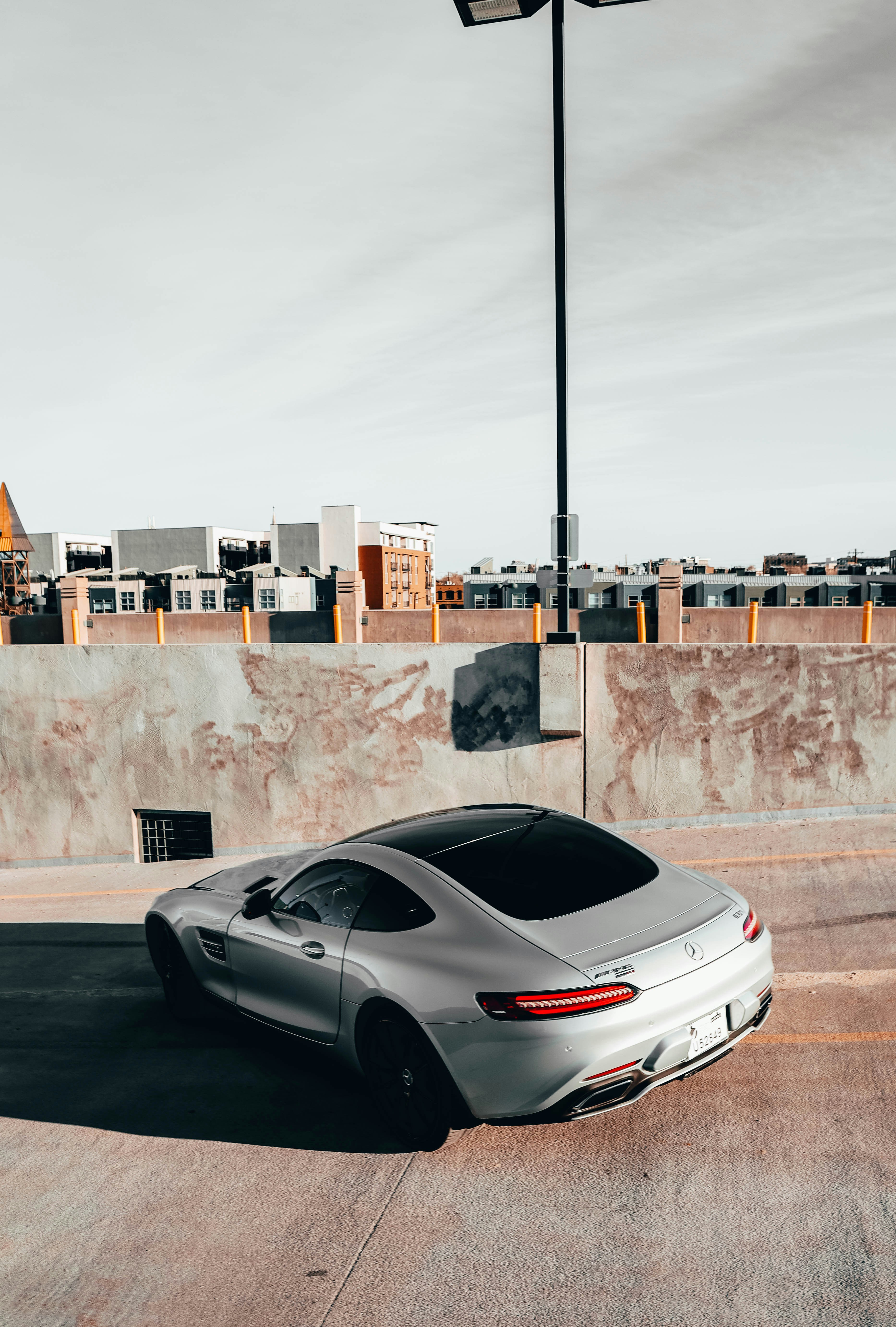 Silver Mercedes-Benz AMG GT parked on city street at dusk with ambient lighting