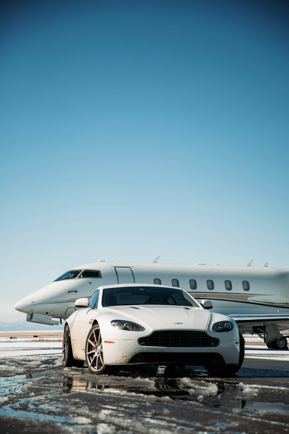 a white car is parked in front of a private jet