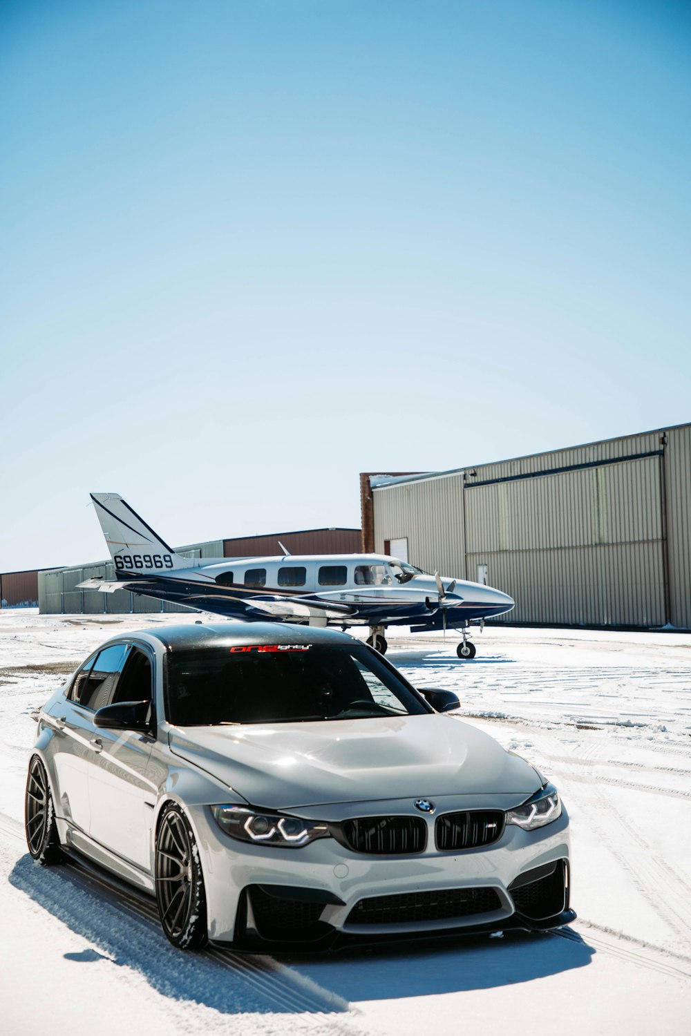 a white car parked in front of an airplane