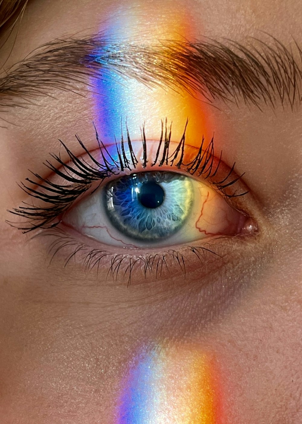 a woman's eye with a rainbow painted on it