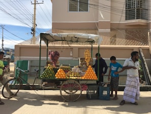 A vendor's cart filled with fresh fruit and crushed ice, kept cool on a busy street.