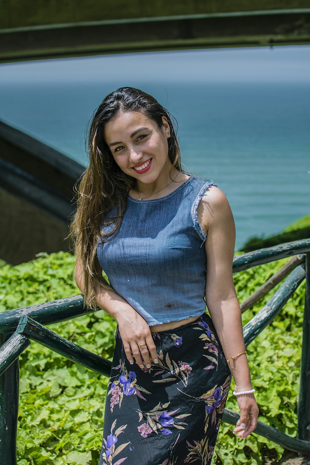 a woman standing on a railing near the ocean