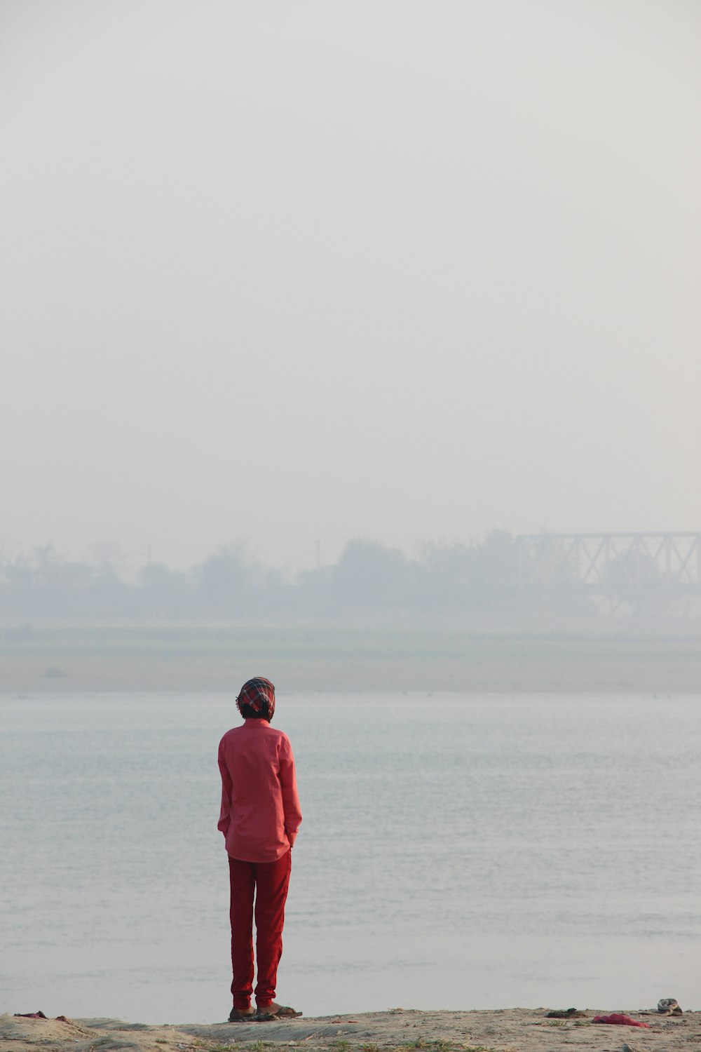 a man standing on a beach next to a body of water