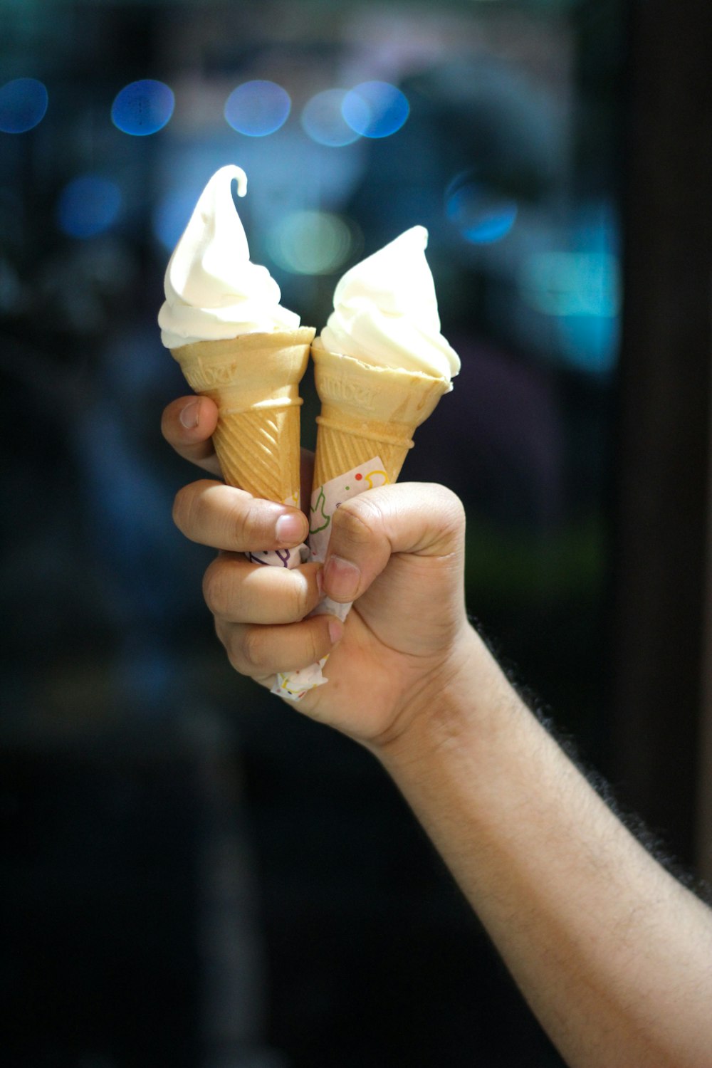 a person holding two ice cream cones in their hand