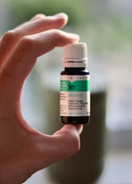 a hand holding a bottle of tea tree essential oil