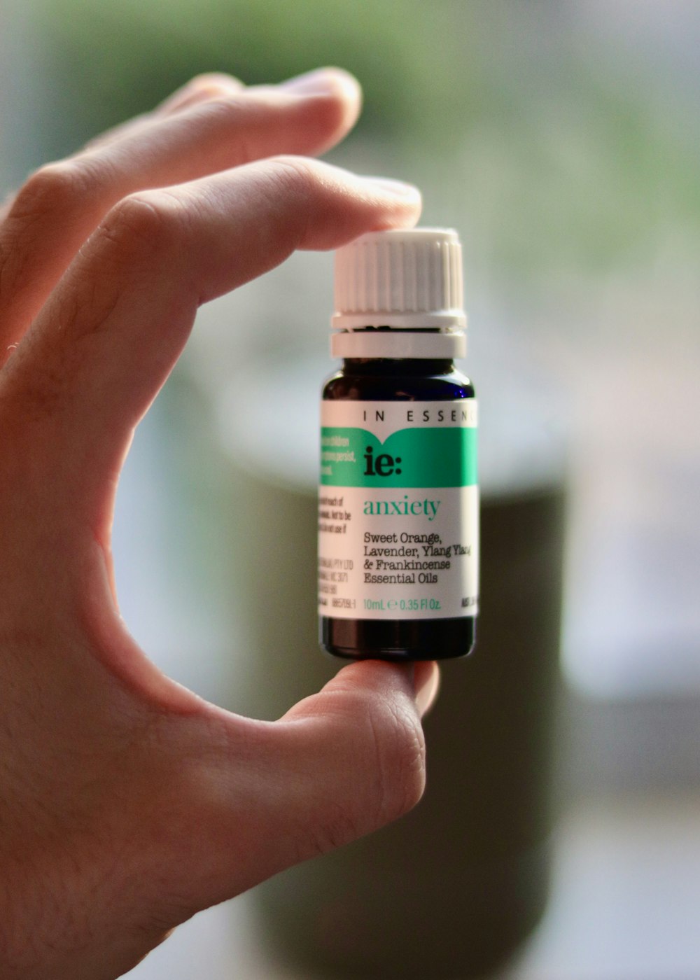 a hand holding a bottle of tea tree essential oil