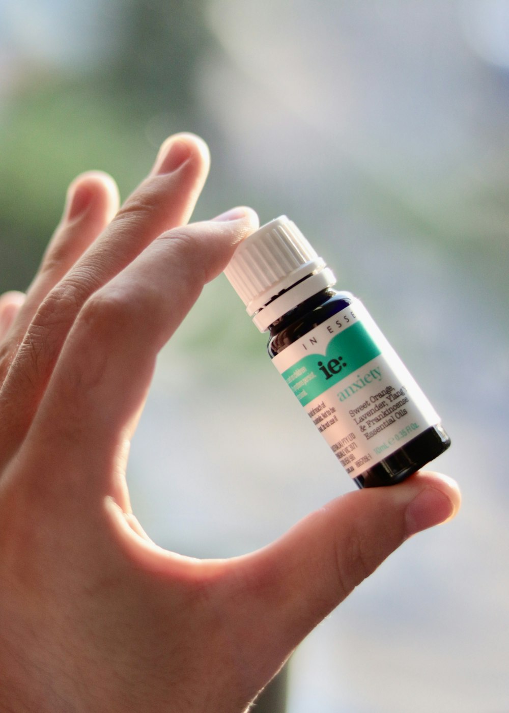 a hand holding a small bottle of essential oils