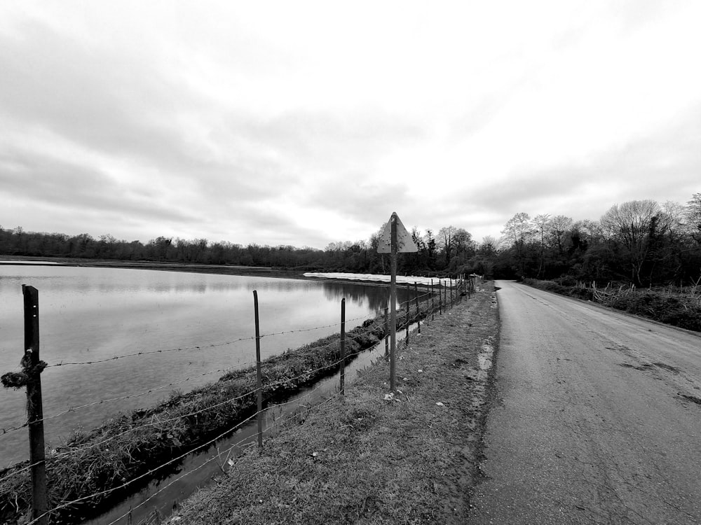 a black and white photo of a road next to a body of water