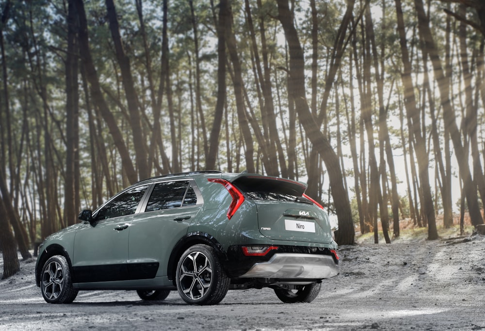 the rear end of a green car parked in a forest