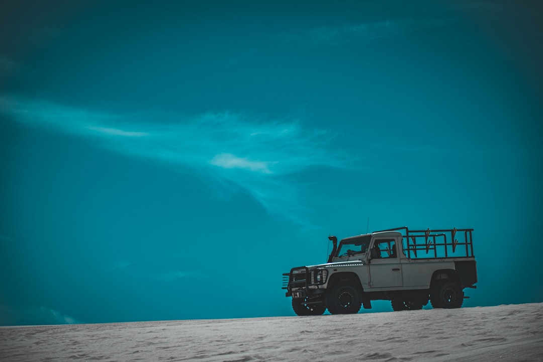 a truck is parked in the sand under a blue sky,