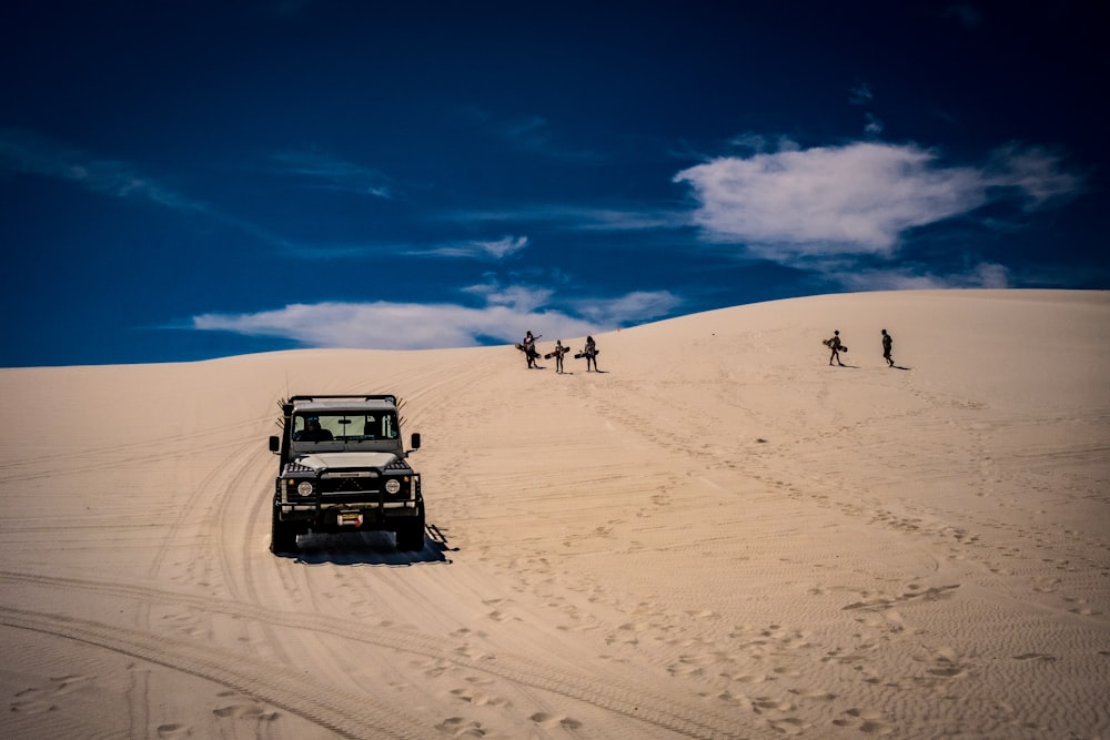 Ein Jeep fährt einen sandigen Hügel in der Wüste hinunter