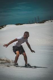 A thrilling shot of someone sandboarding down a golden dune under a bright blue sky.