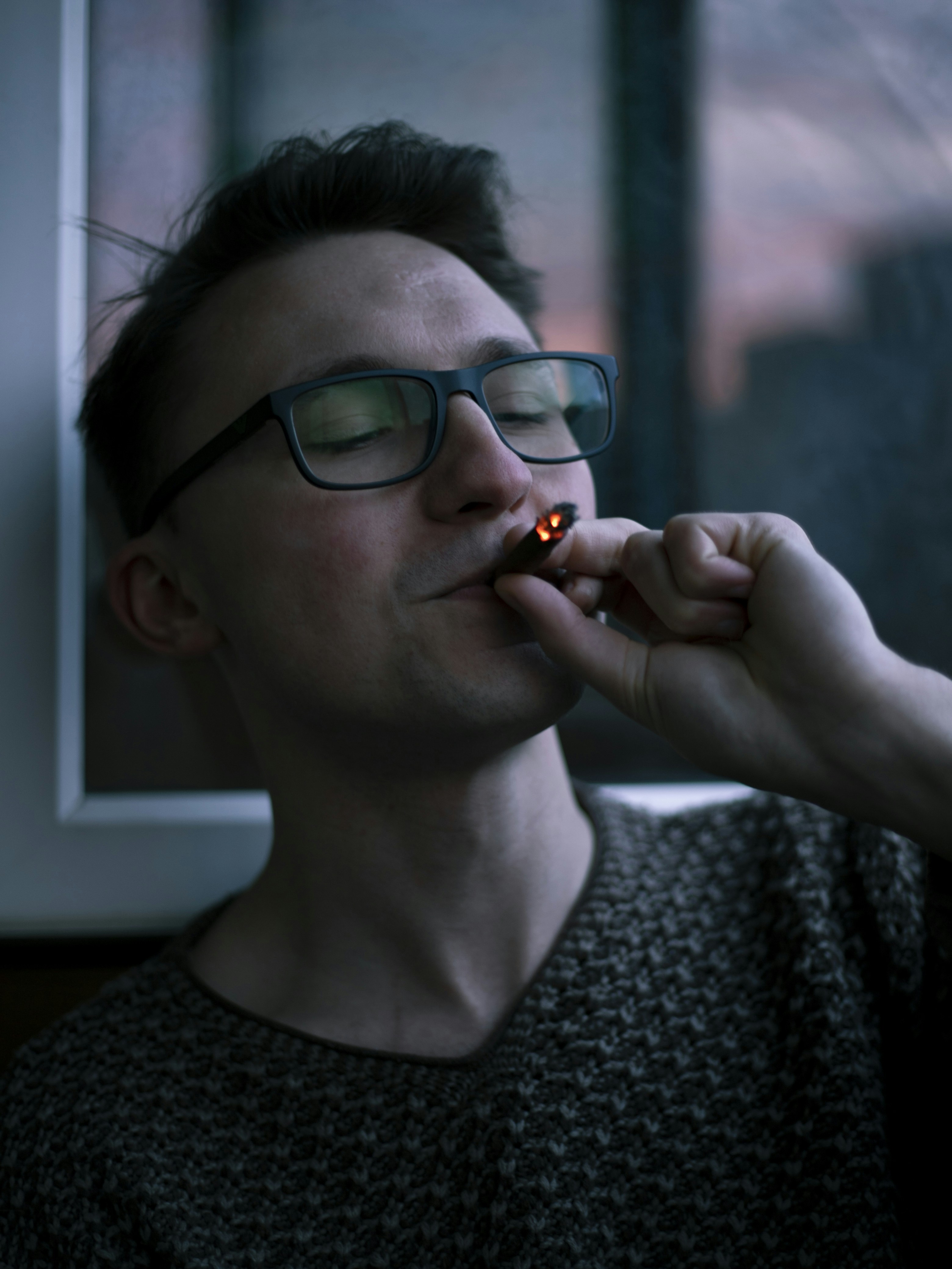 a man with glasses is putting something in his mouth