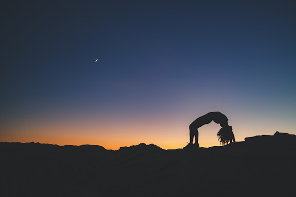A silhouette of a person practicing dynamic meditation at sunrise on a hilltop.