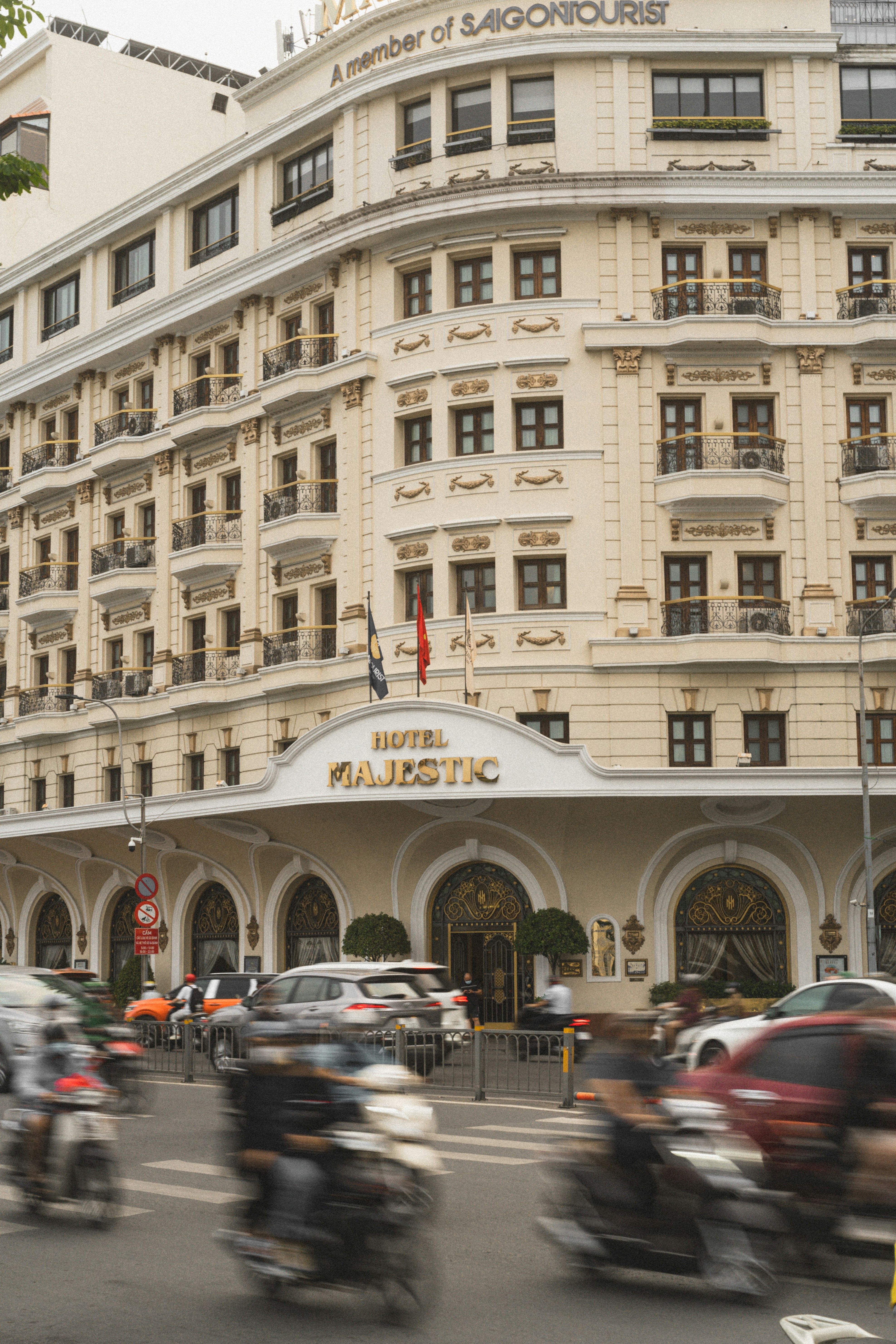 a group of motorcyclists driving down a street in front of a hotel