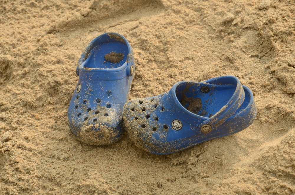 a pair of blue shoes sitting on top of a sandy beach