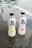 Two bottles of Genki sparkling water are placed on a gray stone surface. The bottle on the left has a citrus lemon flavor, depicted by an image of a lemon slice, while the bottle on the right features a peach flavor, illustrated by a peach image. The bottles are transparent with black caps and display bold black and red text.