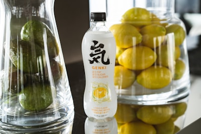 A vibrant bottle of goro's sparkling natural beverage resting on a sunlit wooden table with fresh fruit around it.