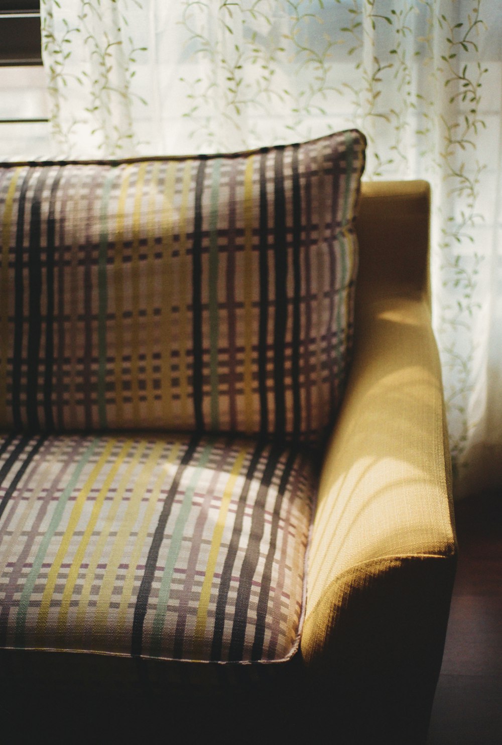 a couch sitting in front of a window next to a curtain