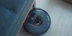 a robotic vacuum is on the floor next to a couch