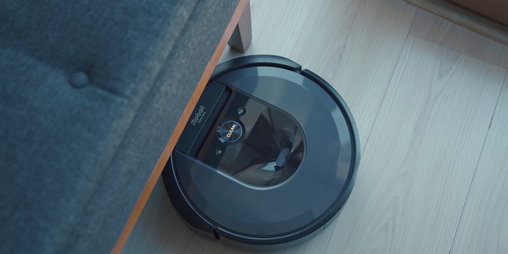 Un aspirapolvere robotico è sul pavimento accanto a un divano