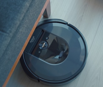 a robotic vacuum is on the floor next to a couch