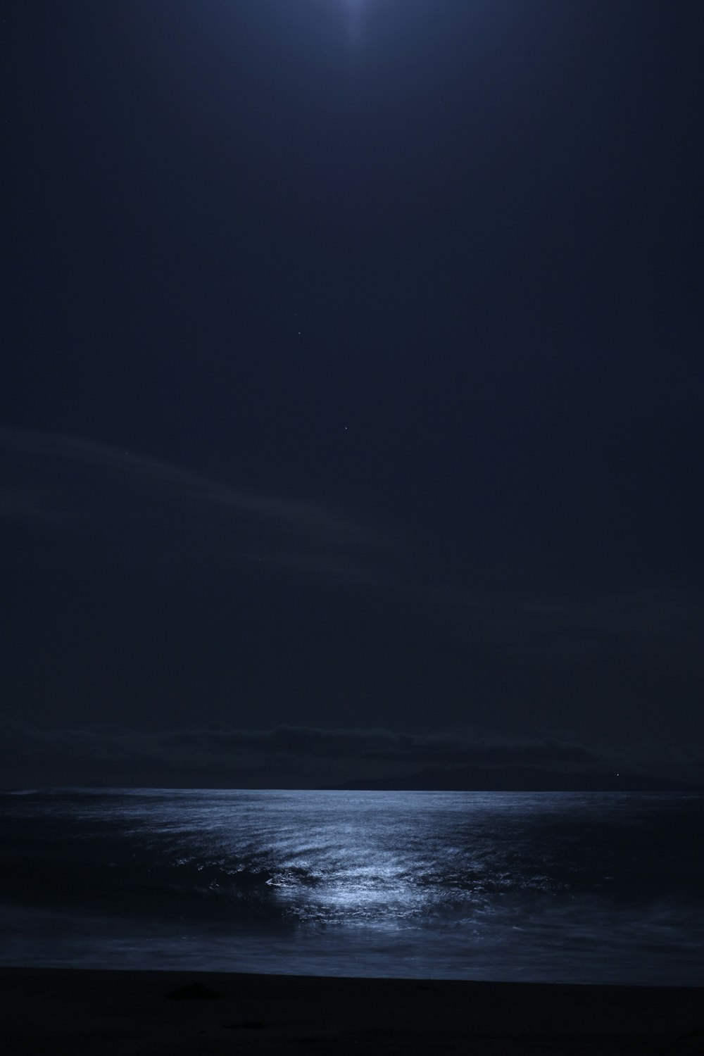 a full moon shines over the ocean at night