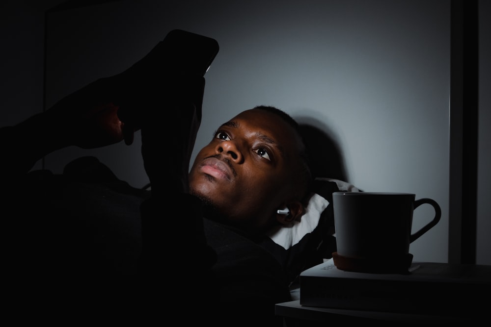 a woman laying on a bed next to a coffee cup