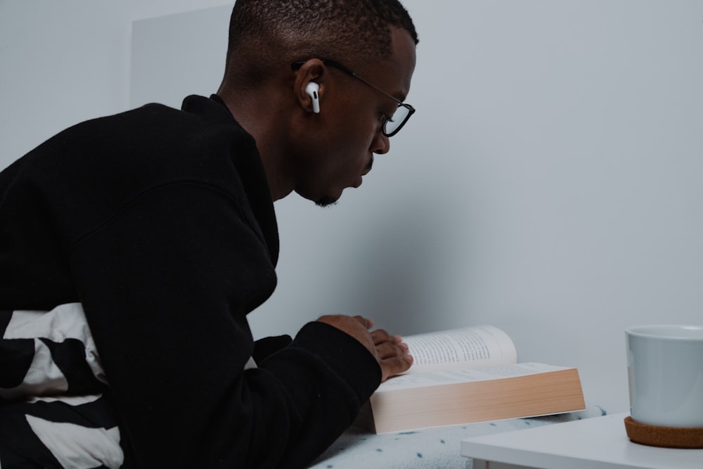 Un hombre sentado en una mesa leyendo un libro