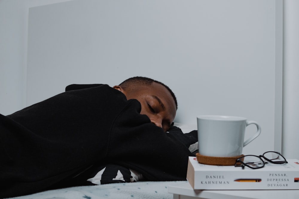 a man sleeping on a bed next to a stack of books