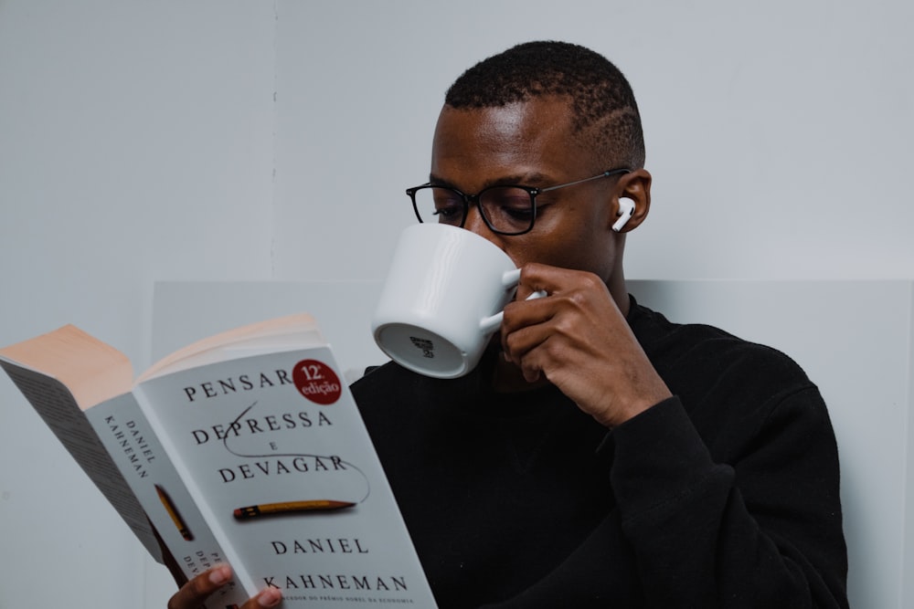 a man holding a coffee mug and reading a book
