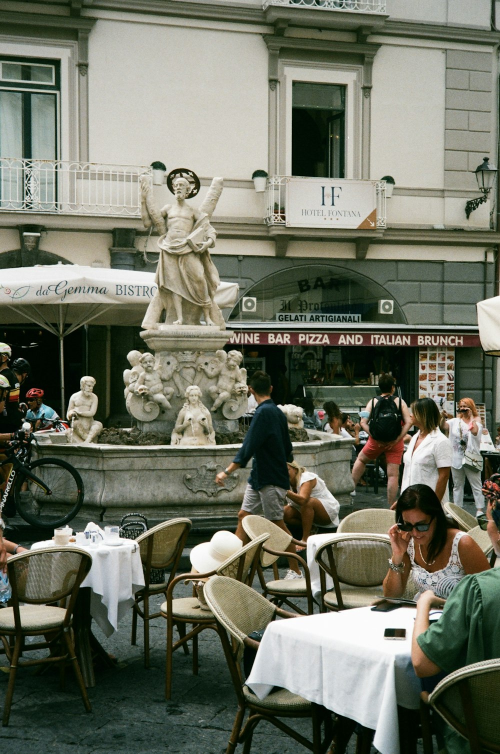 a group of people sitting at tables in front of a fountain