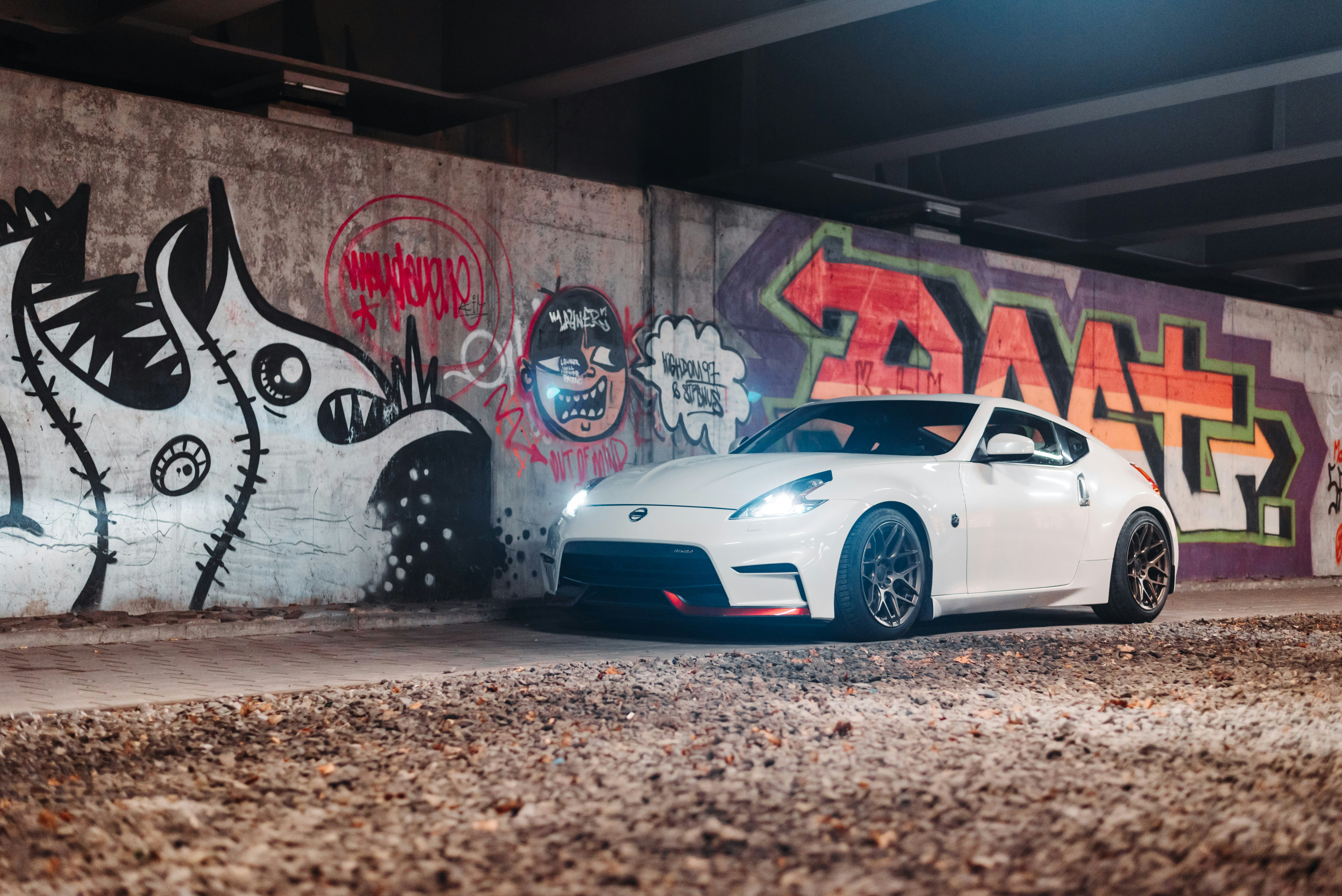 a white sports car parked in front of a graffiti covered wall