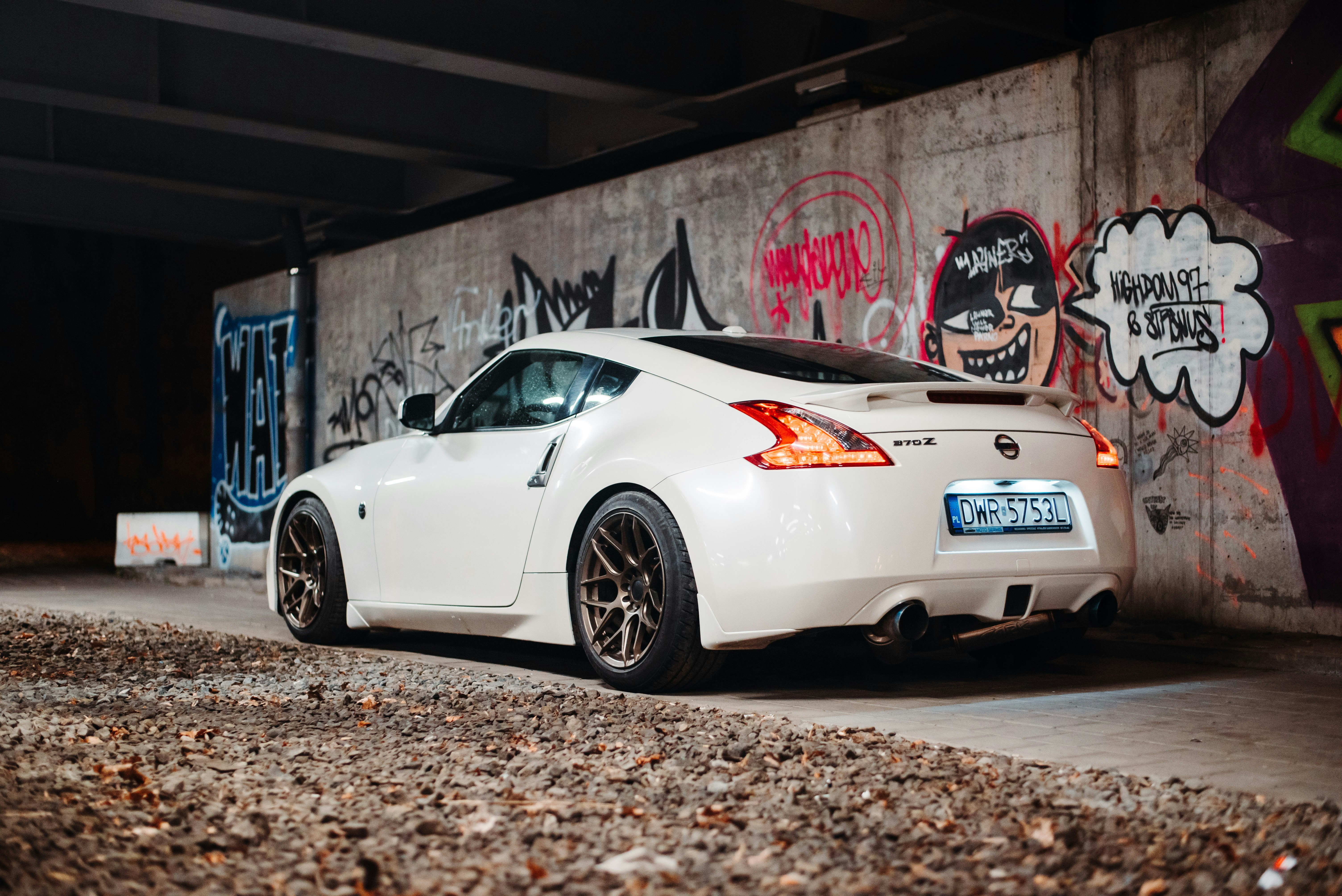 a white sports car parked in front of a graffiti covered wall