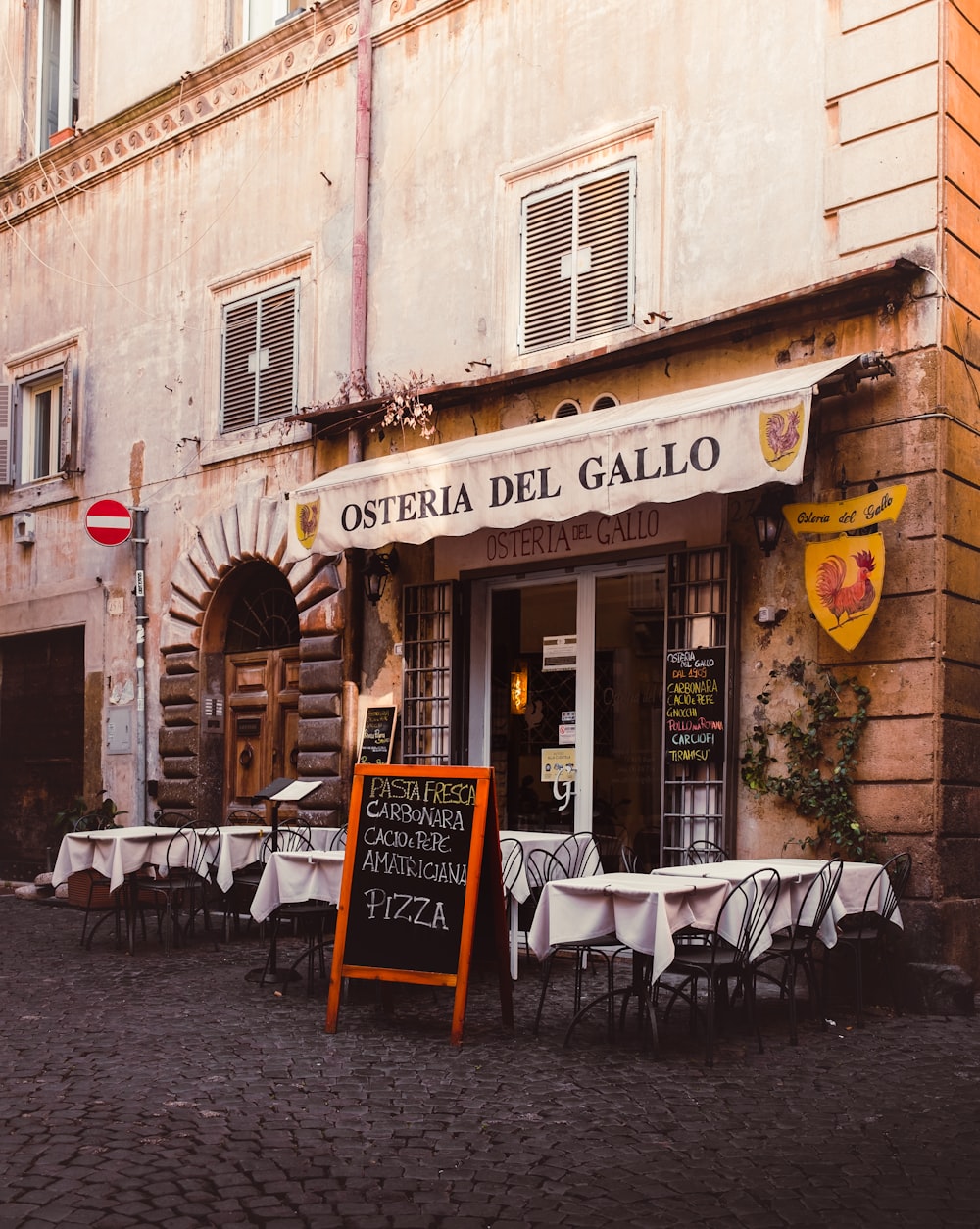 a restaurant called osteria del gallo on a cobblestone street