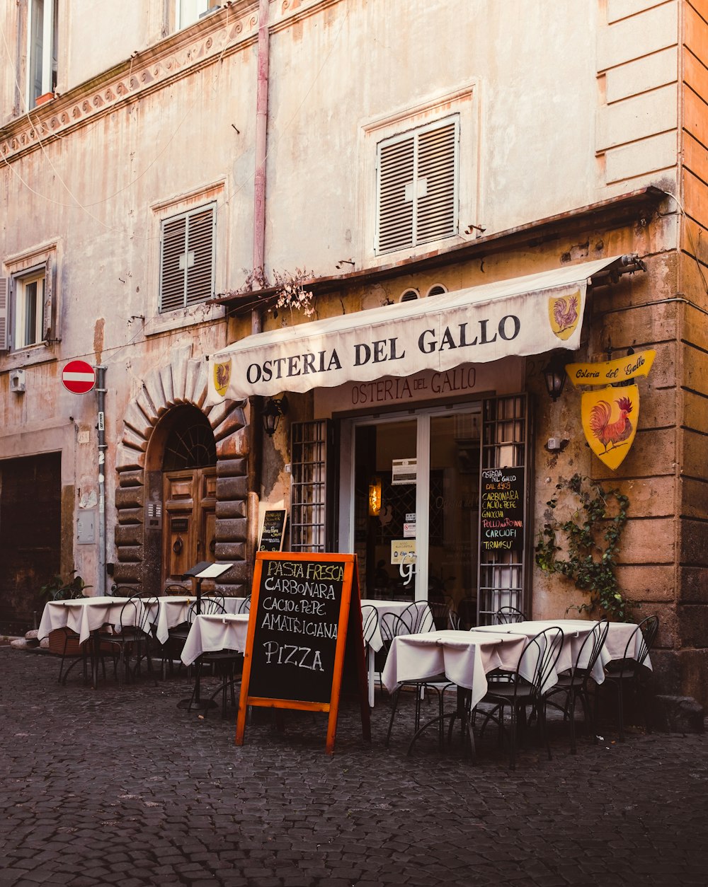 a restaurant called osteria del gallo on a cobblestone street