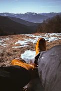 A rugged hiking boot stepping through pristine snow with wildroar branded winter socks visible above the cuff against a backdrop of jagged mountains.