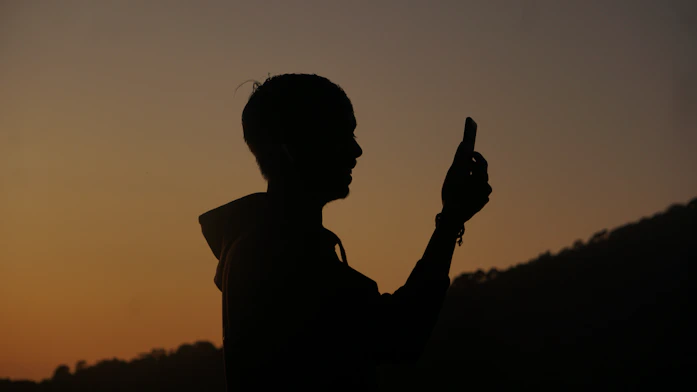 a silhouette of a person holding a cell phone