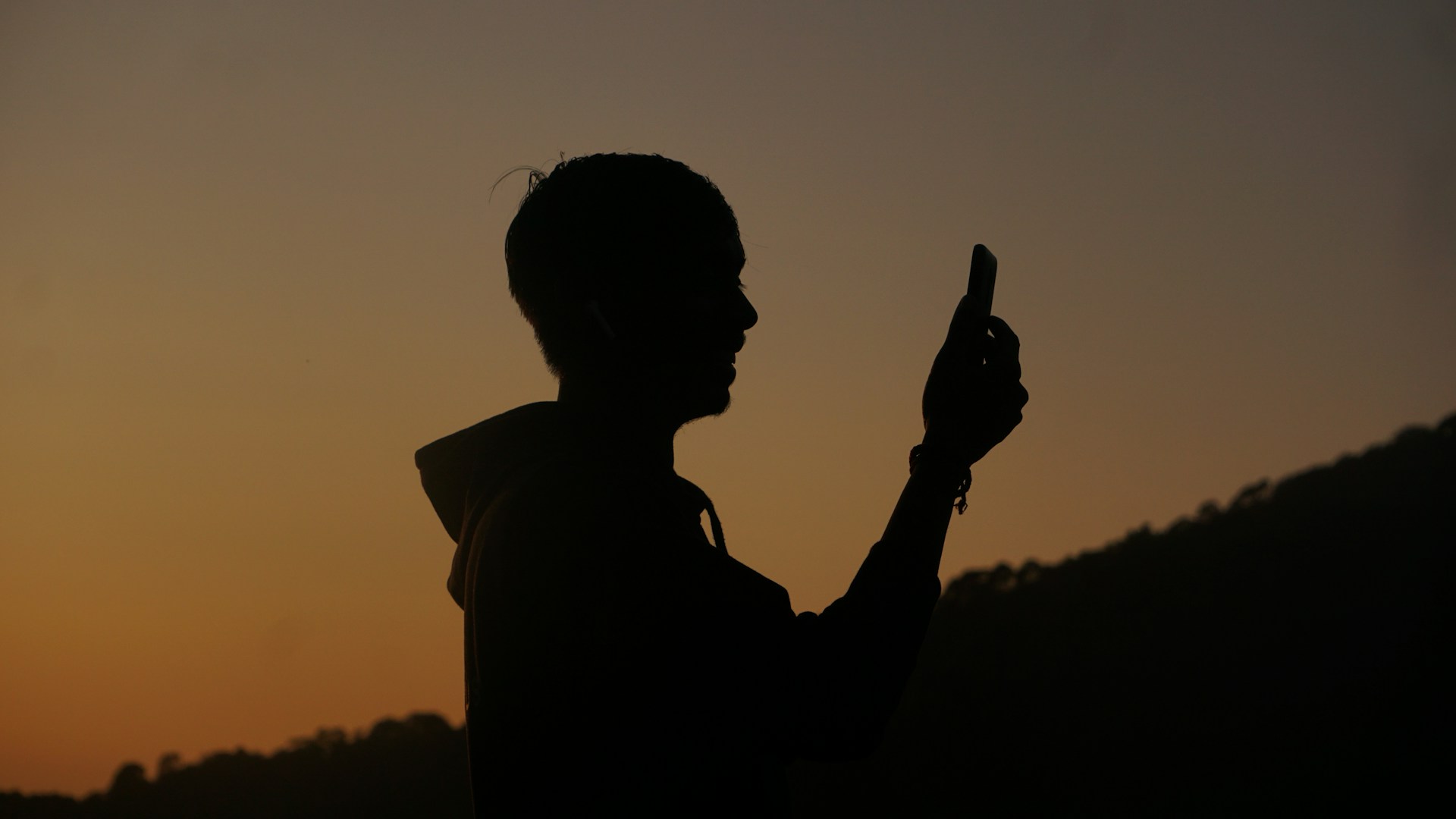 a silhouette of a person holding a cell phone