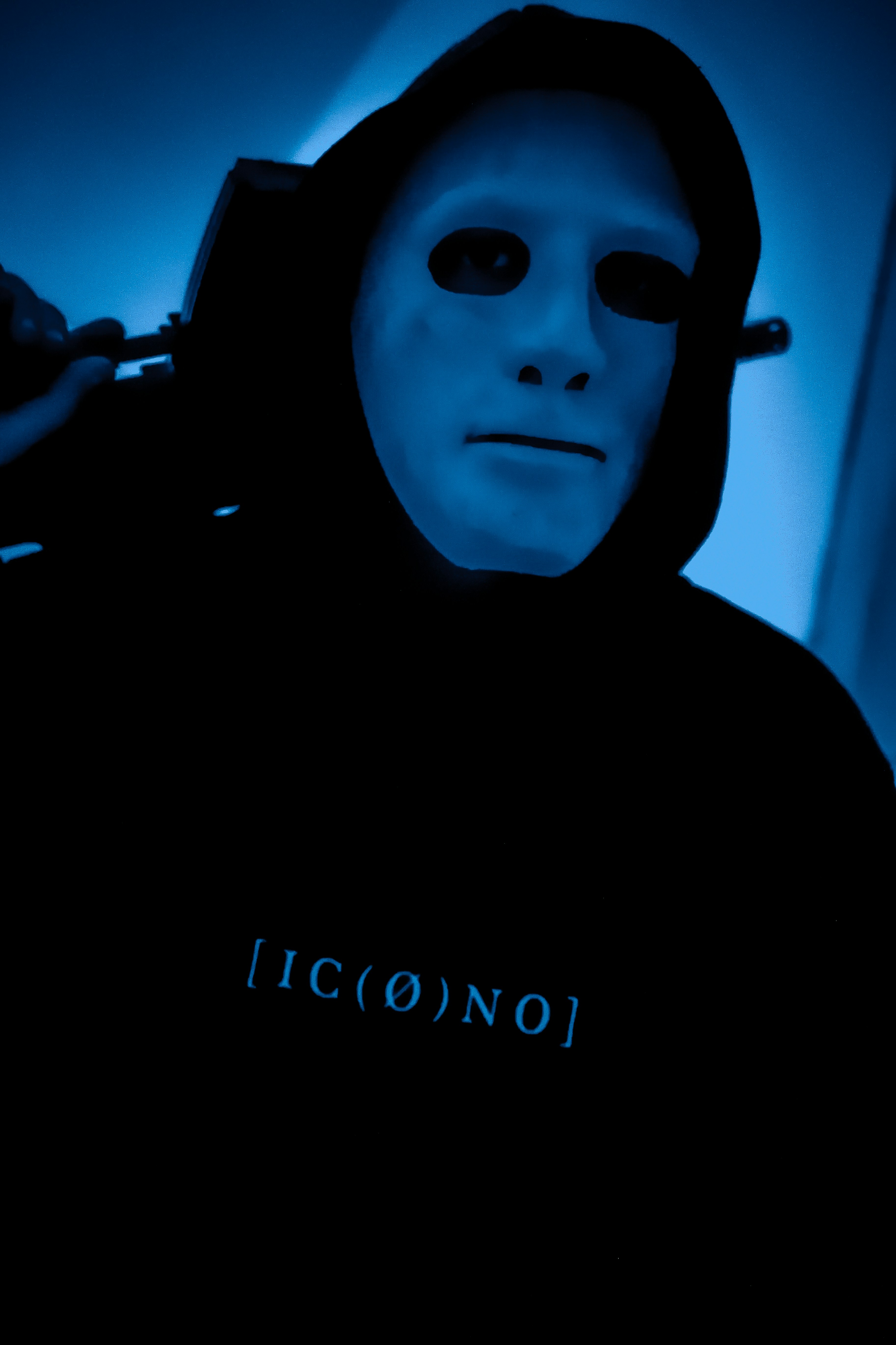 Un homme vêtu d’un sweat à capuche noir avec un fond bleu fluo