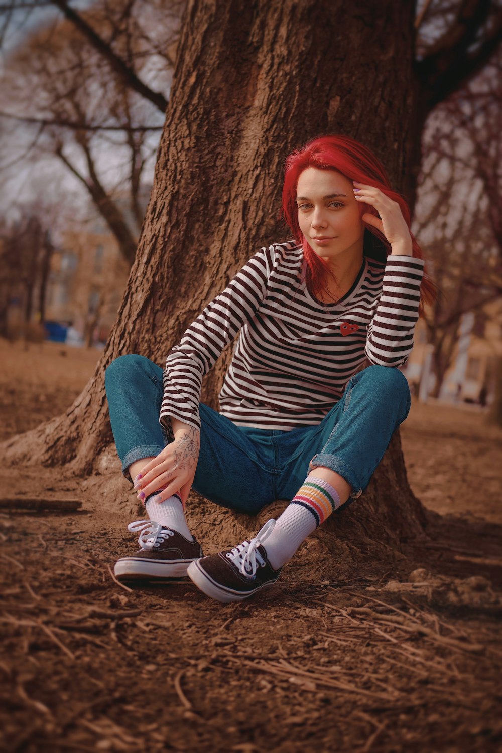 a woman sitting on the ground next to a tree