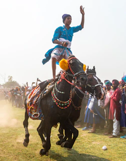 The groom arriving on a decorated horse, surrounded by dancing family and friends in festive attire.