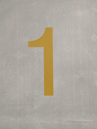a yellow number one on a cement wall