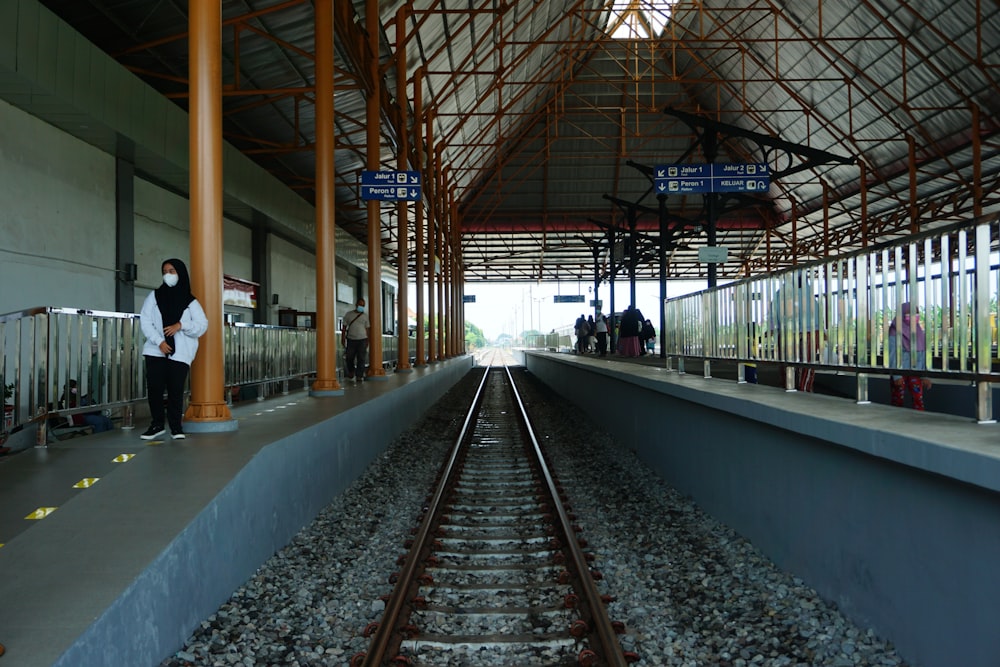 a woman standing on a train track in a train station