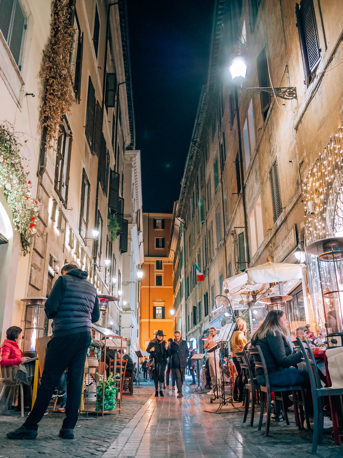 Rua estreita de Roma à noite com pessoas a passear