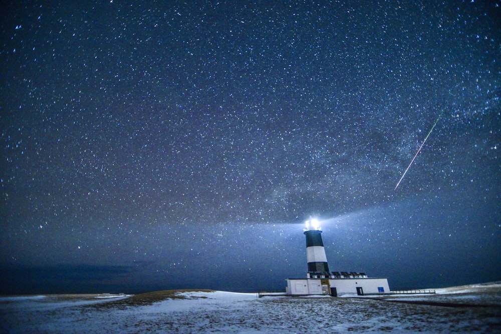 a lighthouse under a night sky filled with stars