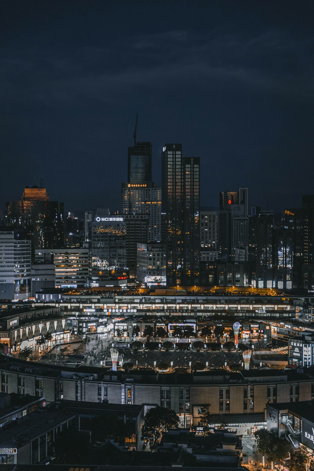 a city skyline at night with a train station in the foreground