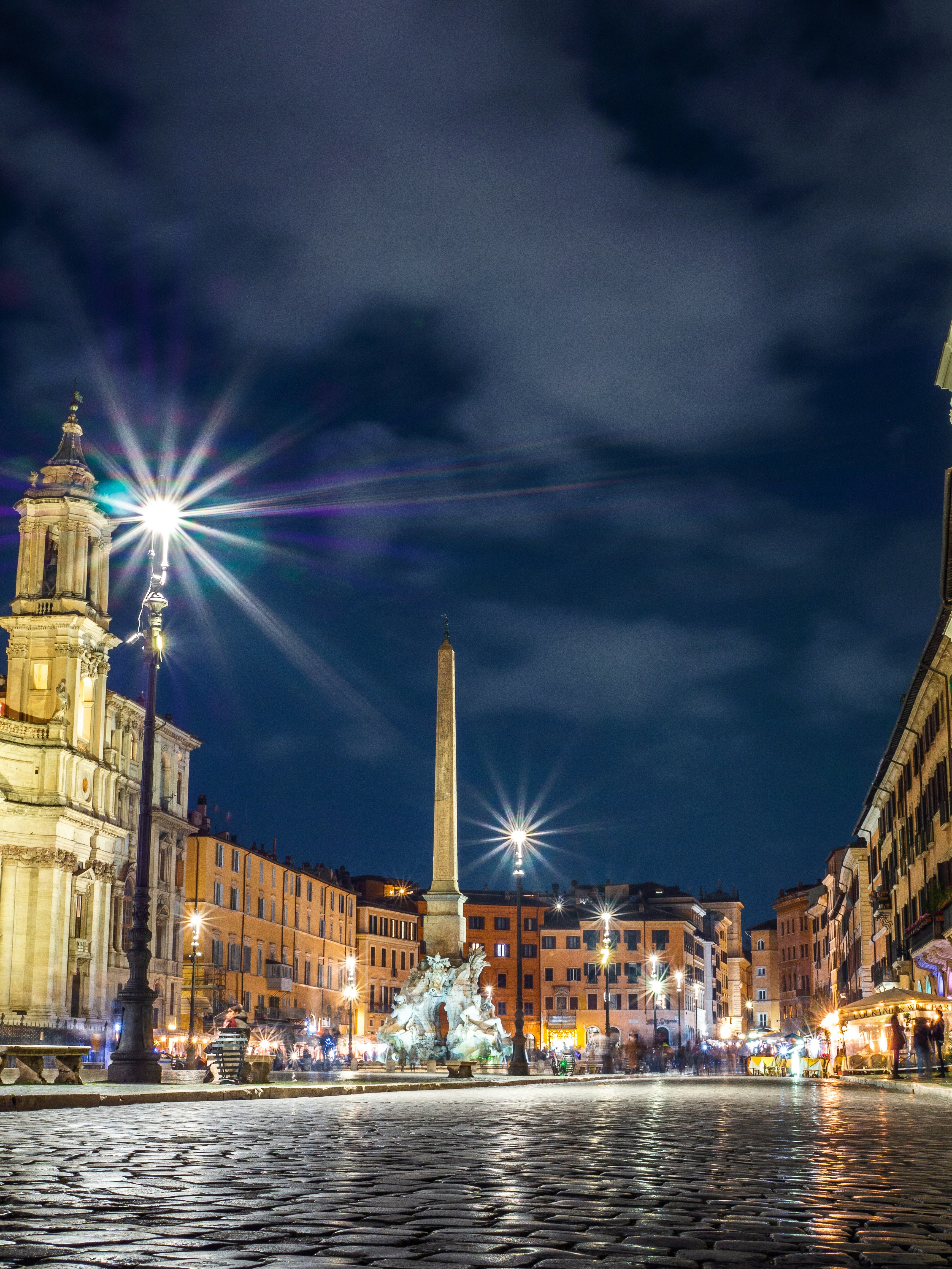 Eine Stadtstraße bei Nacht mit einem Glockenturm im Hintergrund