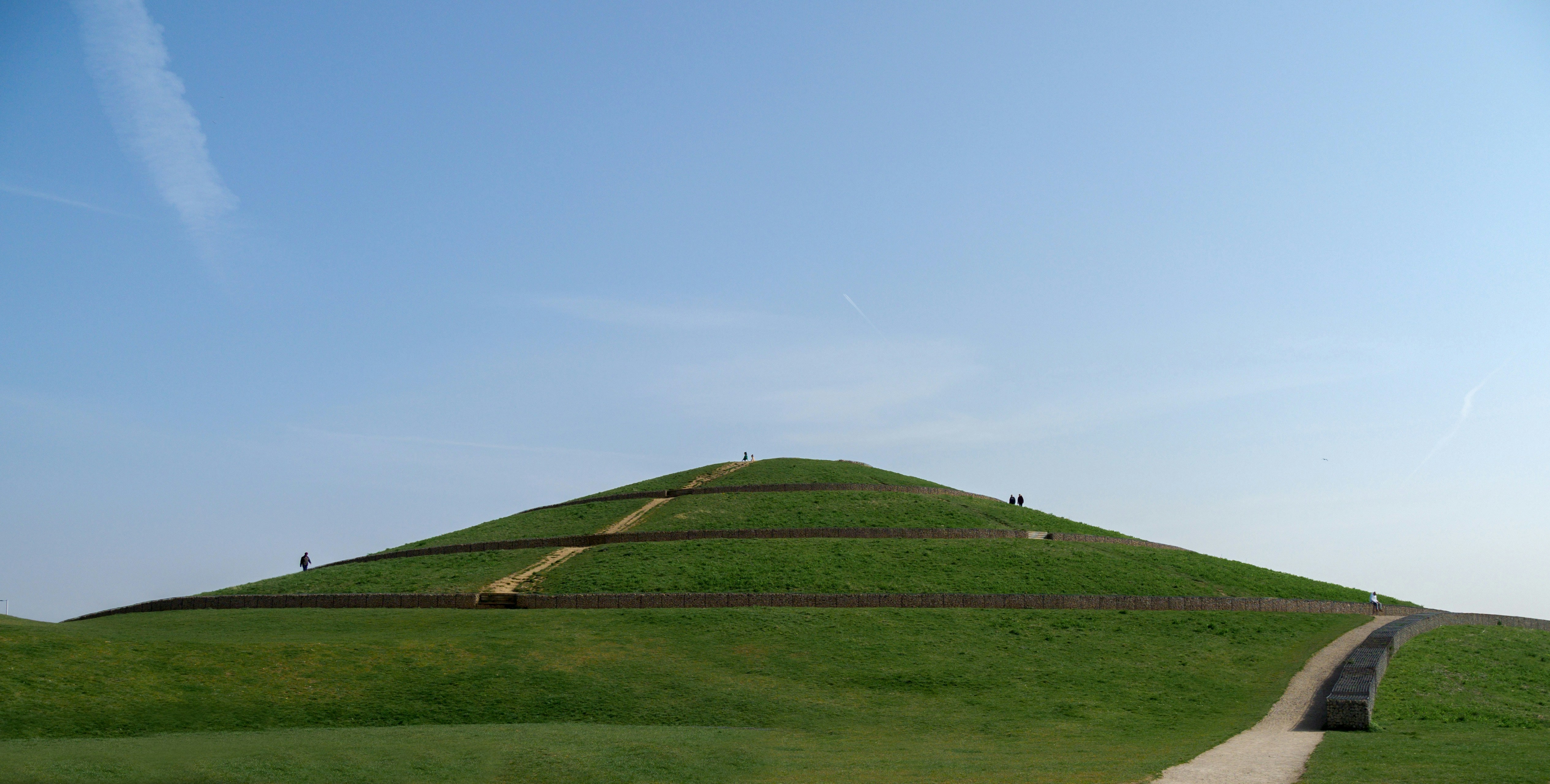 a grassy hill with a long path going up it
