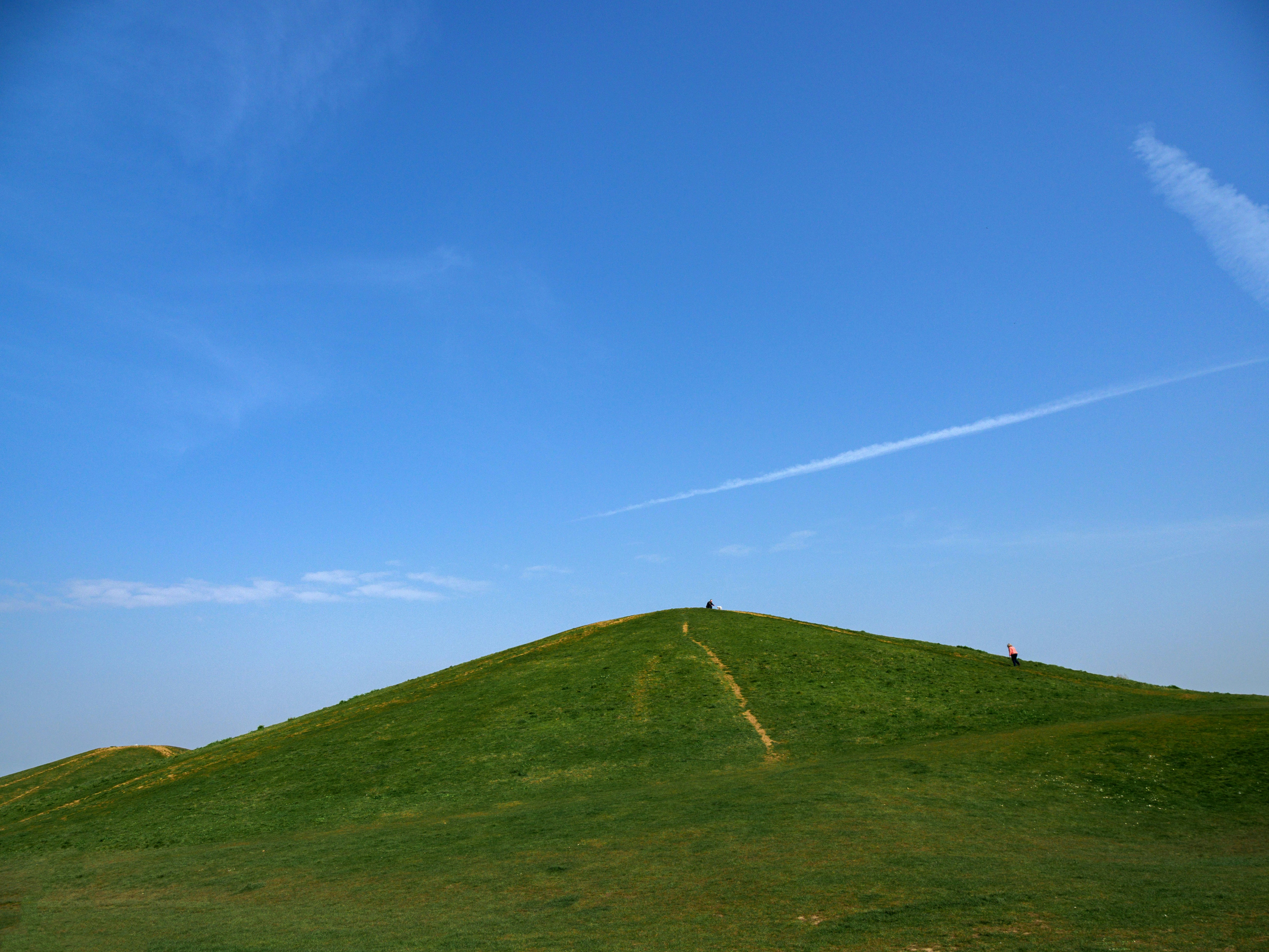 a grassy hill with a person standing on top of it